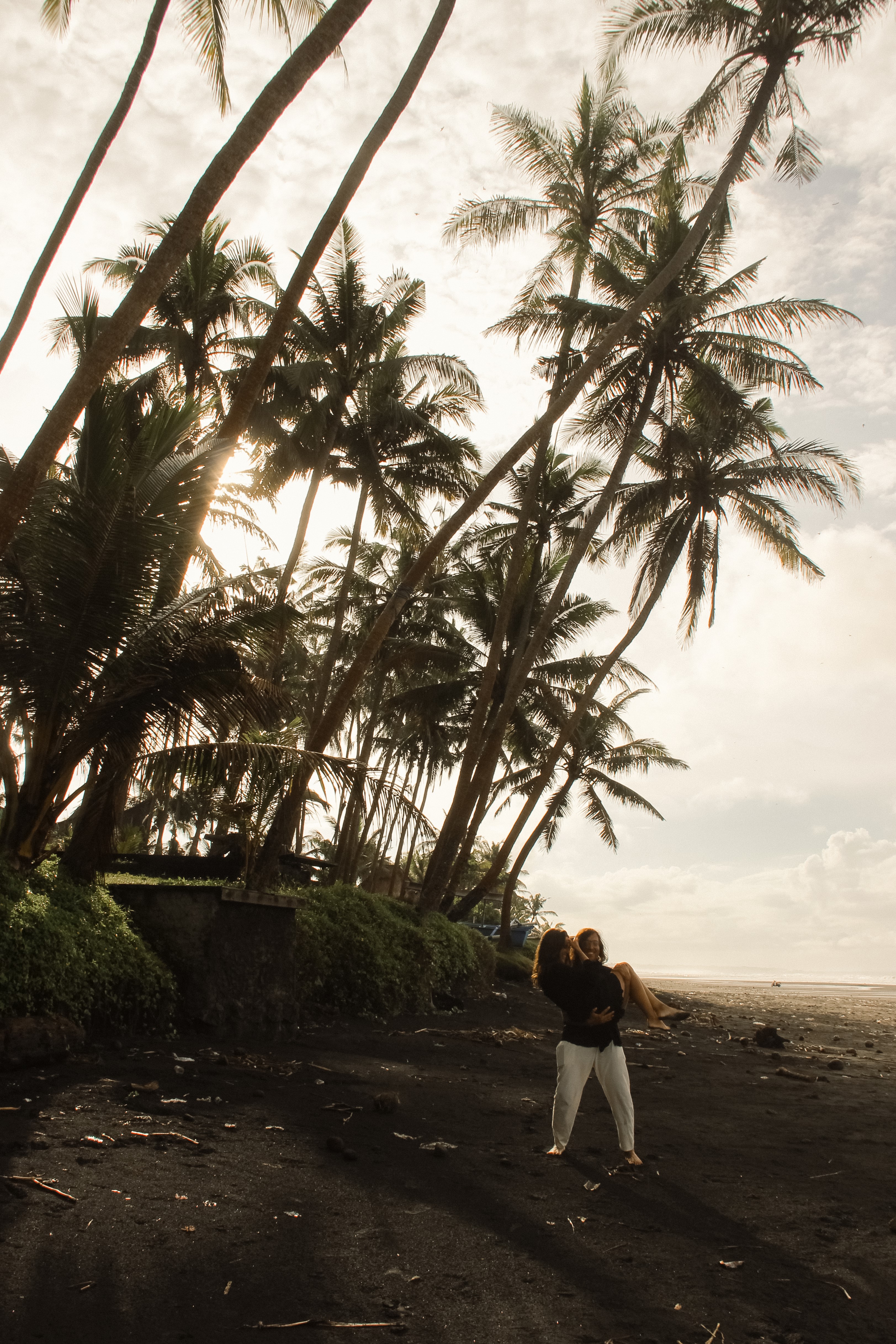 Romantic scene with the couple under palm trees on a tropical beach